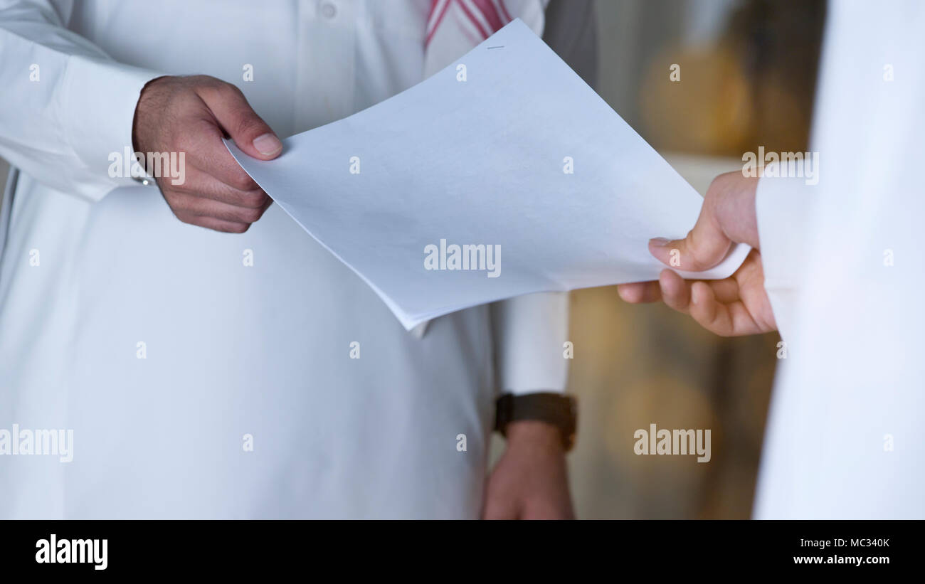 Imprenditore saudita la consegna di un documento cartaceo in un dipendente. Foto Stock