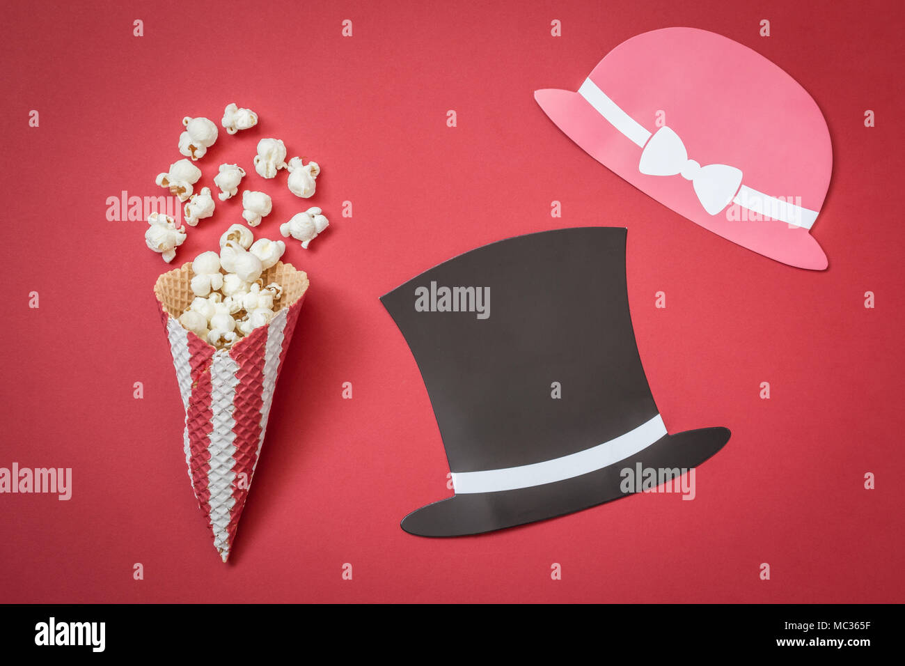 Piatto di laici cono e popcorn con l uomo e la donna carta prop cappelli su sfondo rosso minimal movie theater concept Foto Stock