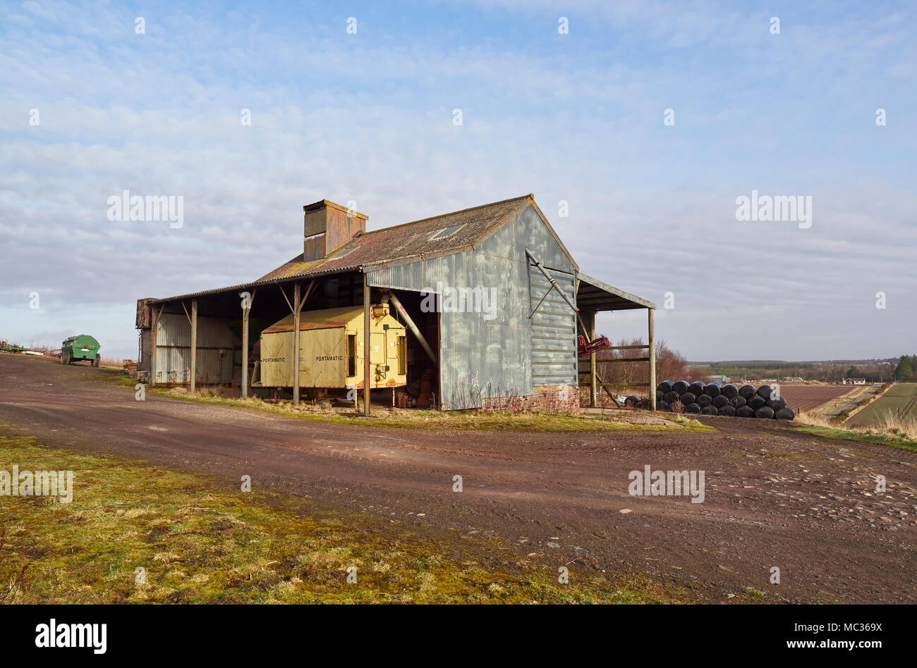 Un vecchio lungo abbandonato Portamatic essiccatore di grano immagazzinato all'interno di un vecchio foglio ondulato fienile rivestito in una fattoria vicino a Dubton, Angus in Scozia. Foto Stock