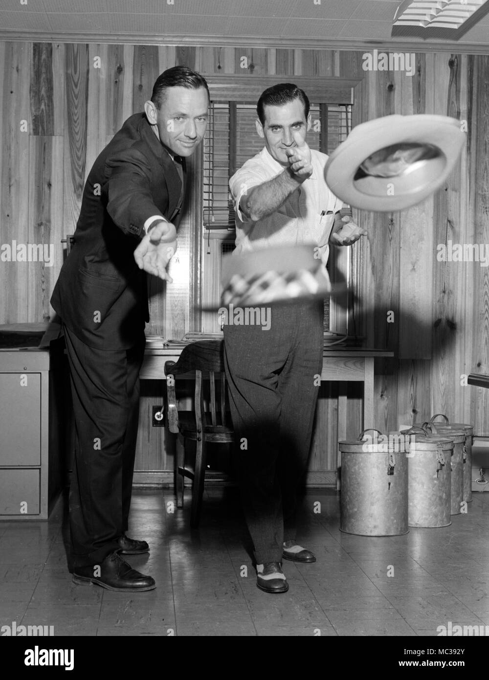 Due uomini sembrano essere lanciare i loro cappelli in un anello, ca. 1962. Foto Stock