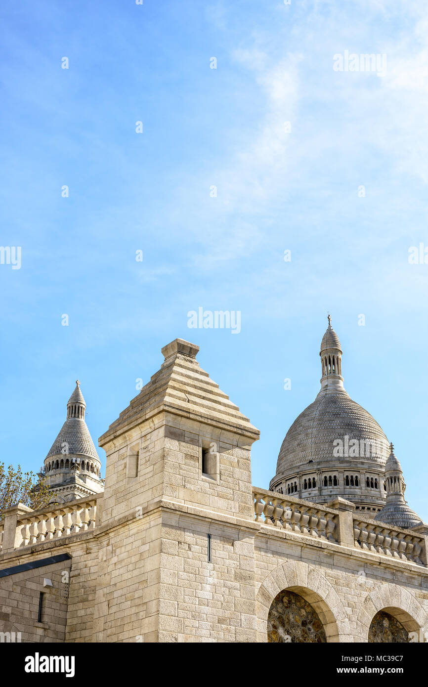 La Basilica del Sacro Cuore di Parigi con la parte esterna della parete di pietra e una torretta del grande serbatoio di acqua di Montmartre in primo piano. Foto Stock