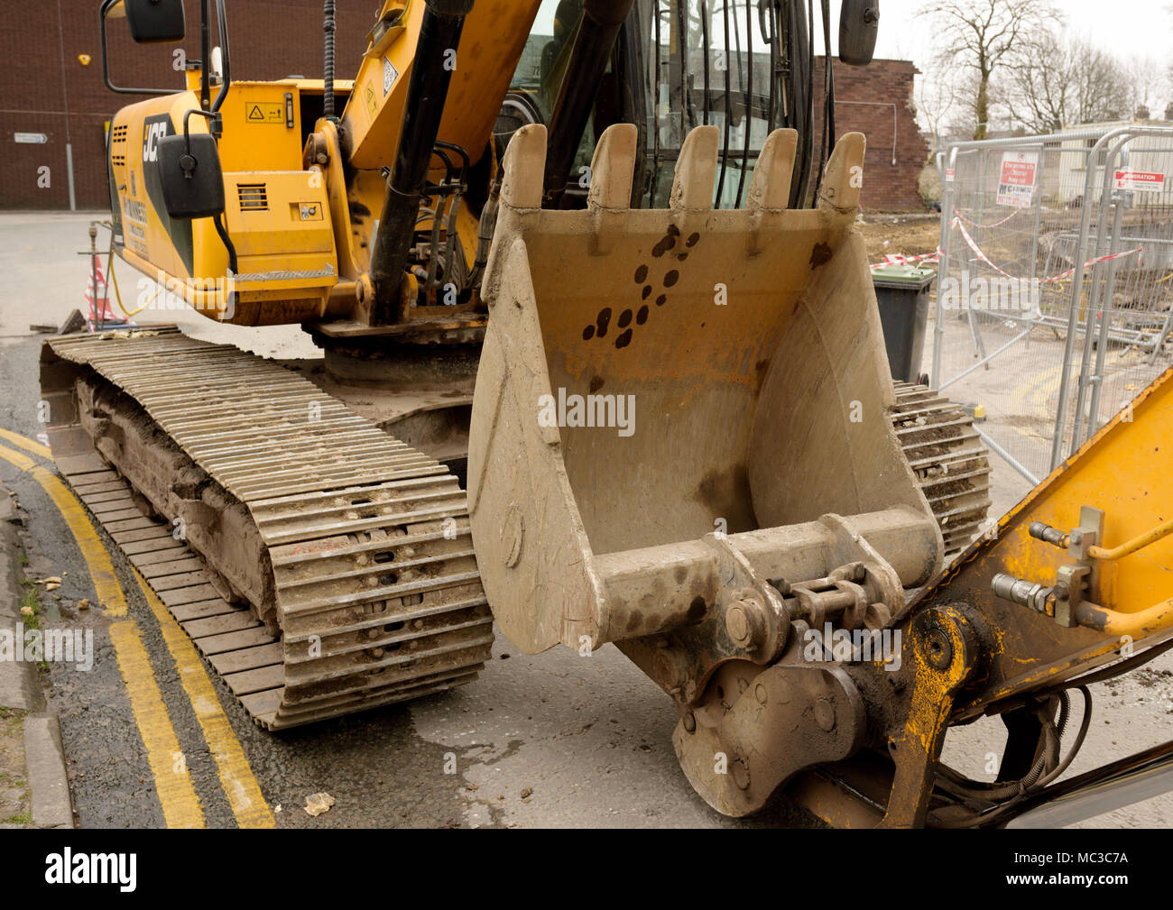 Escavatore cingolato JCB JS220 e benna da scavo su giallo doppio linee accanto al sito di demolizione a bury lancashire uk Foto Stock