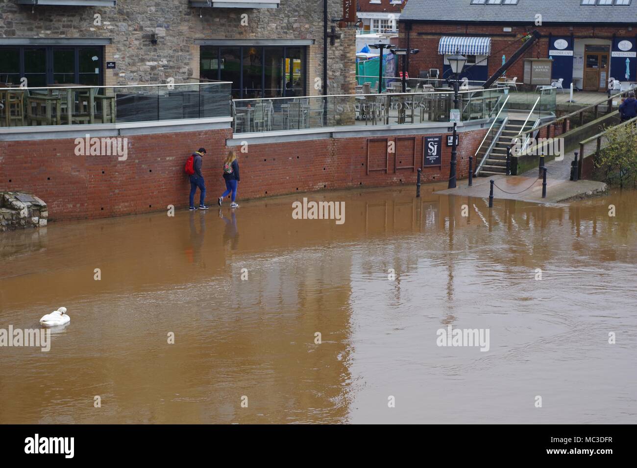 Pedoni negoziare una pavimentazione allagata a Exeter Quay, Devon, Regno Unito. Fiume Exe Flood, aprile 2018. Foto Stock