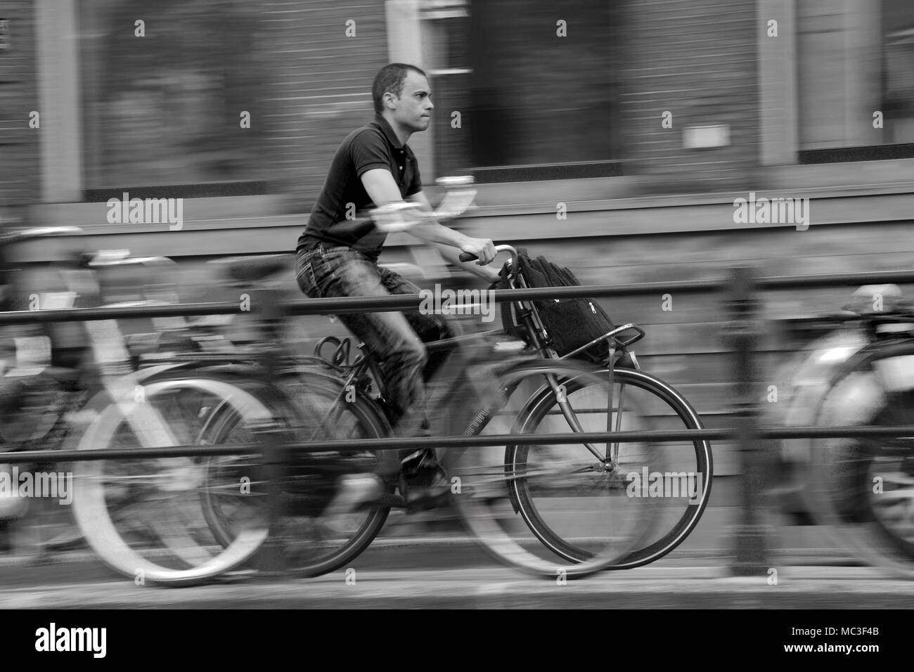 Un uomo su una moto accelerando lungo una strada di Amsterdam Foto Stock