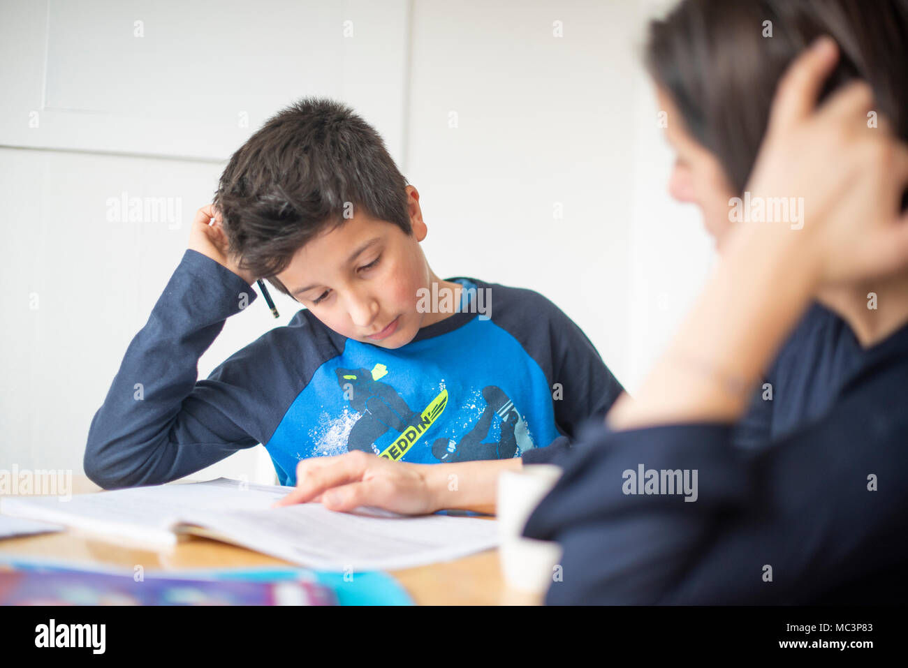Tutoring Privati a casa-10-11 anni ragazzo avente una lezione di matematica a casa-messa a fuoco selettiva Foto Stock