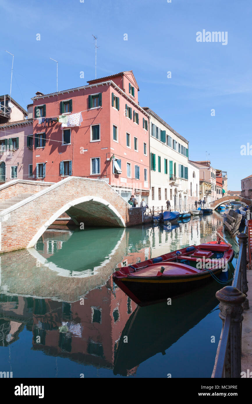 Ponte Nuovo Fondamentin su Rios Sant Anna, Castello, Venezia, Veneto, Italia con riflessioni sul tranquillo canale e barca rossa Foto Stock