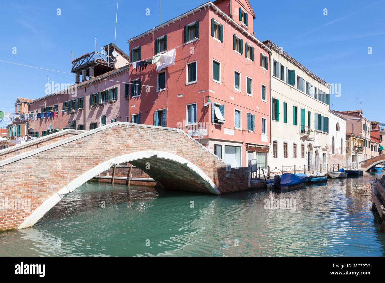 Ponte Nuovo Fondamentin su Rios Sant Anna, Castello, Venezia, Veneto, Italia con riflessioni sul tranquillo canale e case colorate Foto Stock