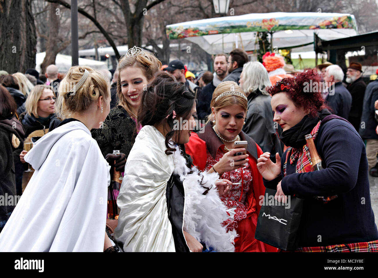 3 donna che guarda al telefono mobile display, Fasching street party, Monaco di Baviera, Baviera, Germania, Europa Foto Stock