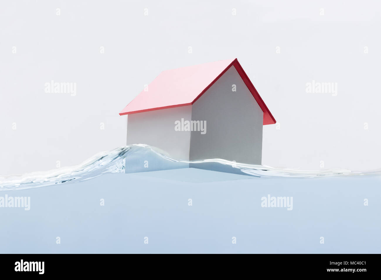 Close-up di un modello di casa con il tetto rosso galleggiante sull'acqua Foto Stock