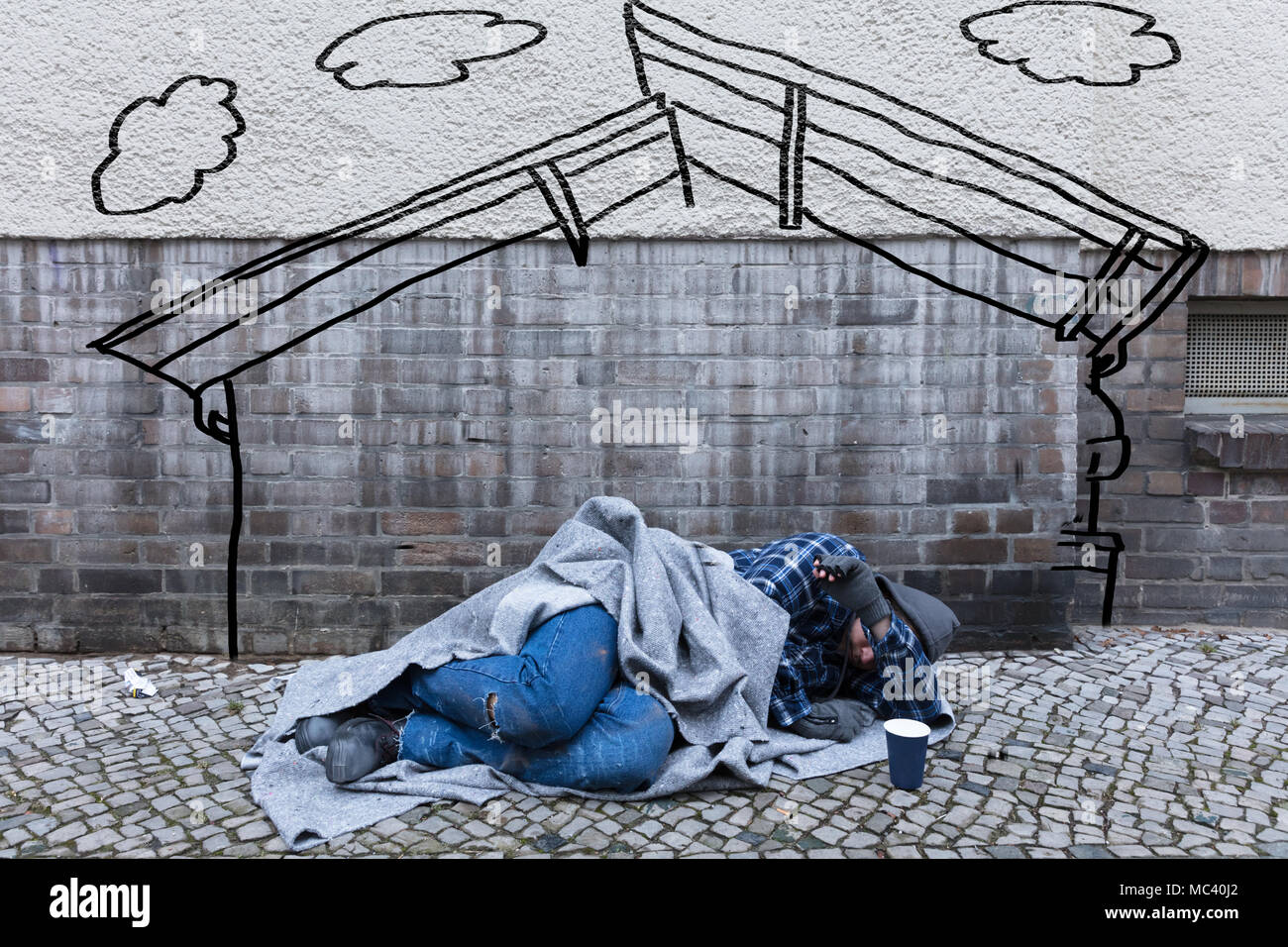 Senzatetto mendicante di dormire sulla strada sotto il disegno di una casa Foto Stock