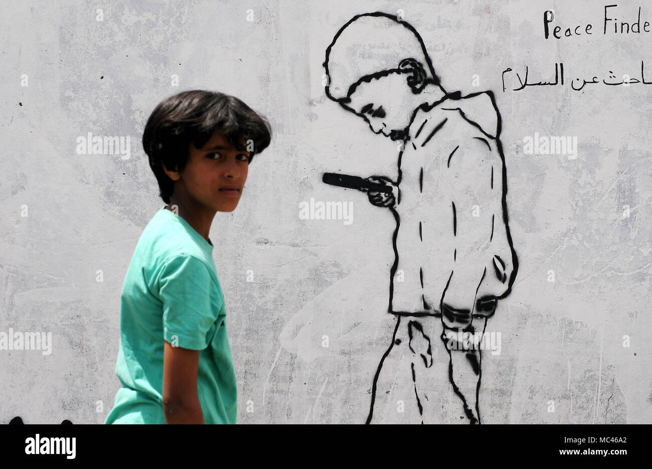 Sanaa, Yemen. Xii Apr, 2018. Un ragazzo cammina da un pezzo di graffiti illustrazione durante un graffiti campagna denominata 'tutti vogliamo la pace, vittime silenziose' in Sanaa, Yemen, il 12 aprile 2018. Gli attivisti yemenita ha organizzato una campagna di graffiti per tracciare la sofferenza delle donne e dei bambini in guerra. Credito: Mohammed Mohammed/Xinhua/Alamy Live News Foto Stock