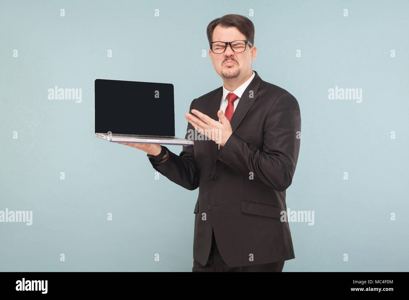 Business, gadget,tecnologie. Imprenditore azienda Rotte favorite lap top, brutta giornata. Indoor, studio shot, isolato su luce blu o grigio Foto Stock