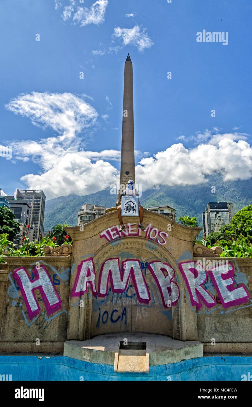Un giovane guerriero seduto in Plaza Francia di Altamira e al di sotto di un graffito è scritto ... Siamo affamati. Caracas, Luglio 6, 2017 Foto Stock