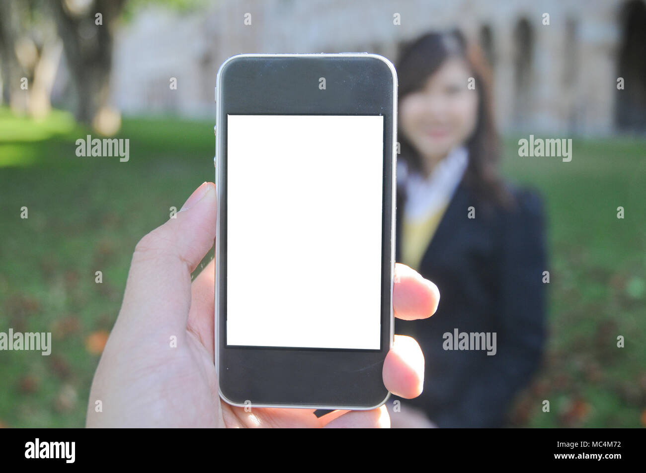 Una mano azienda smart phone a prendere le foto di corporate non identificato lady in un parco Foto Stock
