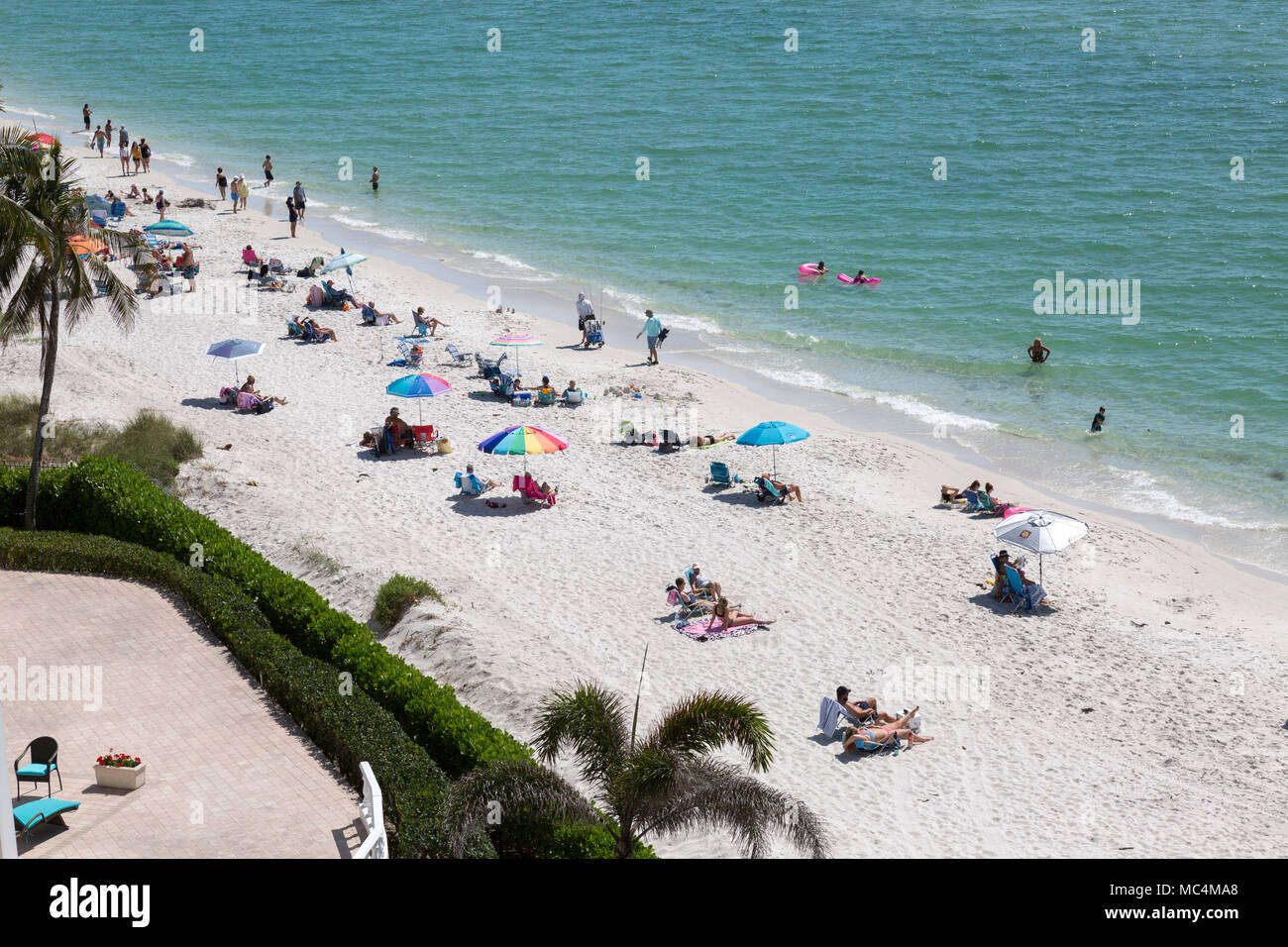 Vista da sopra della scena in spiaggia lungo la costa della Florida in Napoli. Le famiglie in vacanza su spring break. Colorato ombrelloni da spiaggia. Foto Stock