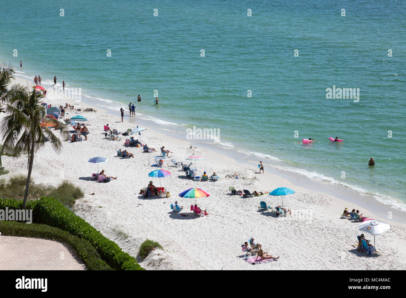 Vista da sopra della scena in spiaggia lungo la costa della Florida in Napoli. Le famiglie in vacanza su spring break. Colorato ombrelloni da spiaggia. Foto Stock