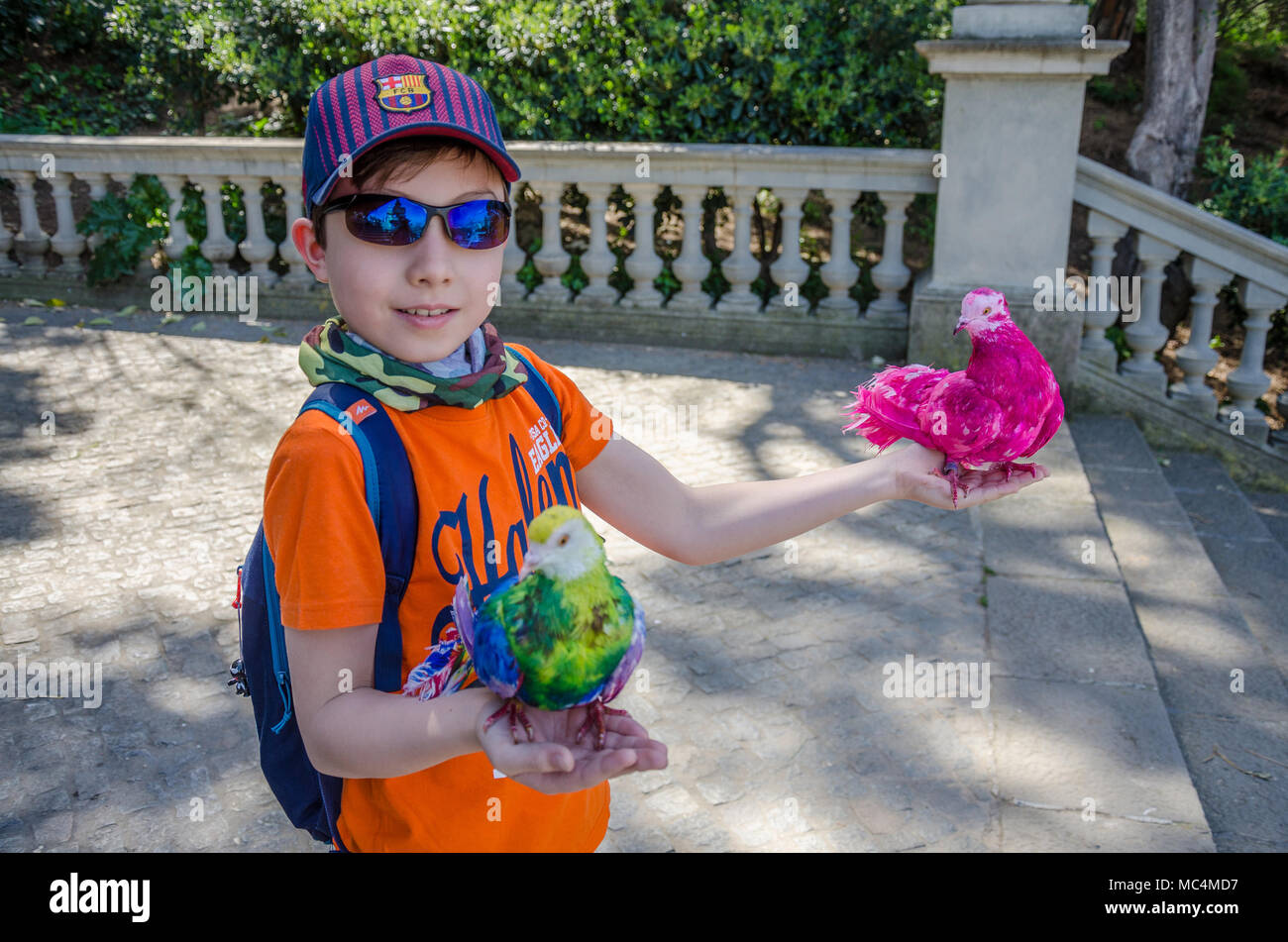 Un giovane ragazzo detiene due tinto piccioni a fiocco su una vacanza a Barcellona, Spagna. Foto Stock