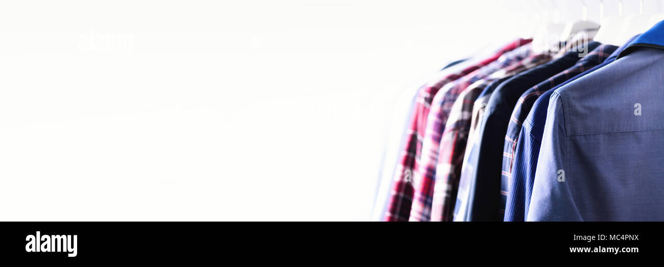 Colore blu vestiti. Abbigliamento maschile, giacche e camicie appeso sul bastone appendiabiti. Copia dello spazio. Banner Foto Stock