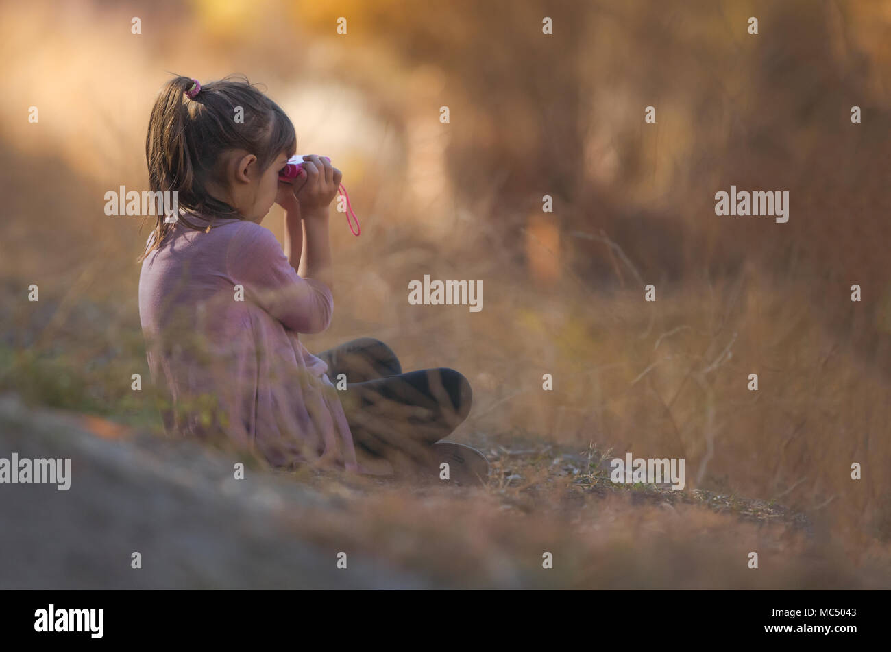 Carina ragazza che gioca nella foresta con un binocolo Foto Stock