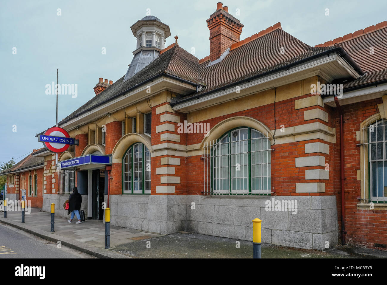 Barkingside, Ilford, Essex, Regno Unito - 6 Aprile 2018: vista esterna di Barkingside stazione della metropolitana con un passeggero in partenza dall'ingresso. Foto Stock