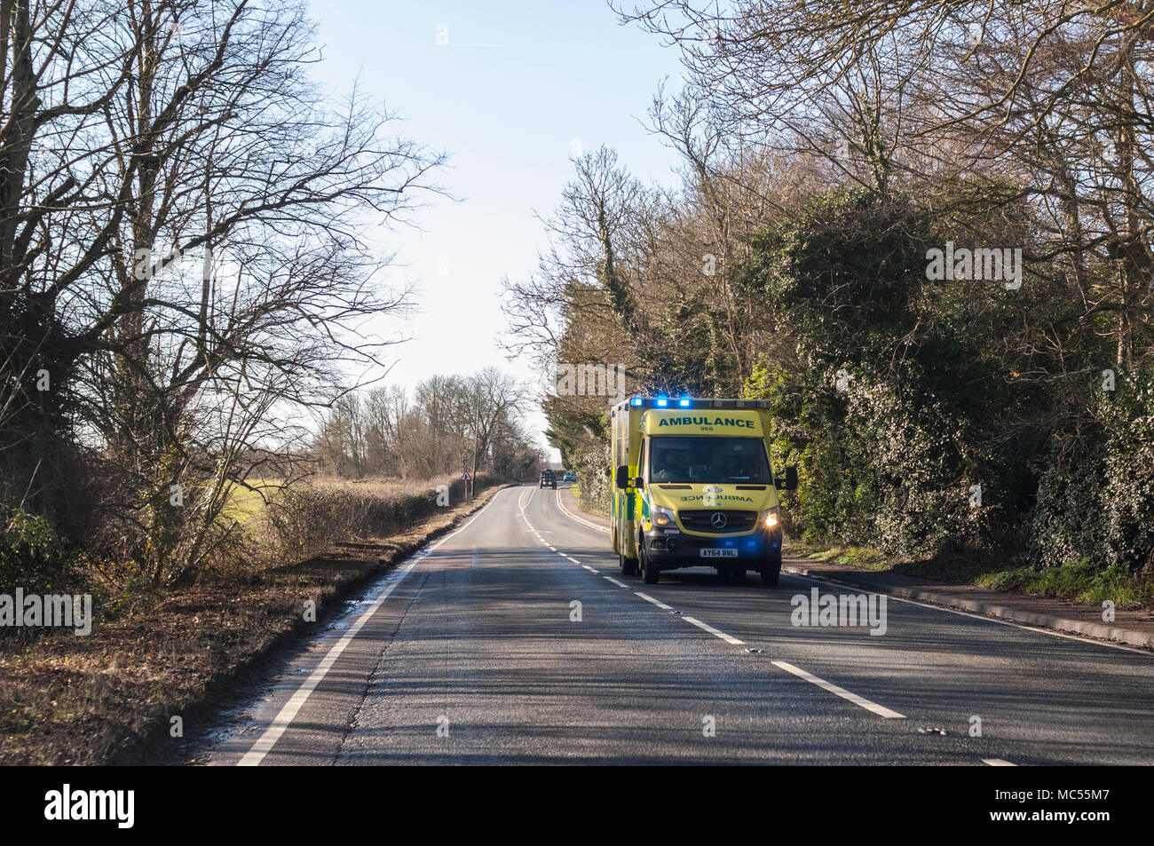Un'ambulanza con luci blu lampeggianti su una strada principale in Norfolk , Inghilterra , Regno Unito Foto Stock