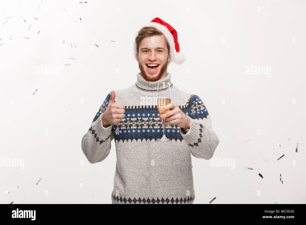 Concetto di natale - Happy giovani caucasici uomo barba holding champagne vetro con sfondo di confetti per celebrare il giorno di Natale. Foto Stock