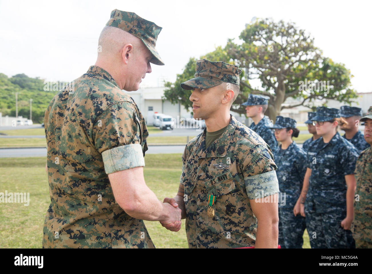 Brig. Gen. Daniel B. Conley, comandante generale, 3° Marine Logistics Group, presenta HM2 Winston Winslett, leader di Petty Officer in carica del Camp Schwab dental clinic, 3° Battaglione dentale, 3° MLG, con la terza MLG il marinaio di l'anno a Camp Foster, Okinawa, in Giappone, 5 aprile 2018. Winslett è stato onorato con il 3° MLG il marinaio di l'anno per conoscere i suoi doveri di LPO per il Camp Schwab clinica dentale, che è una posizione di solito data per una maggiore-classifica Sailor. Winslett è un nativo di Owatonna, Minnesota. (U.S. Marine Corps photo by Lance Cpl. Isabella Ortega) Foto Stock