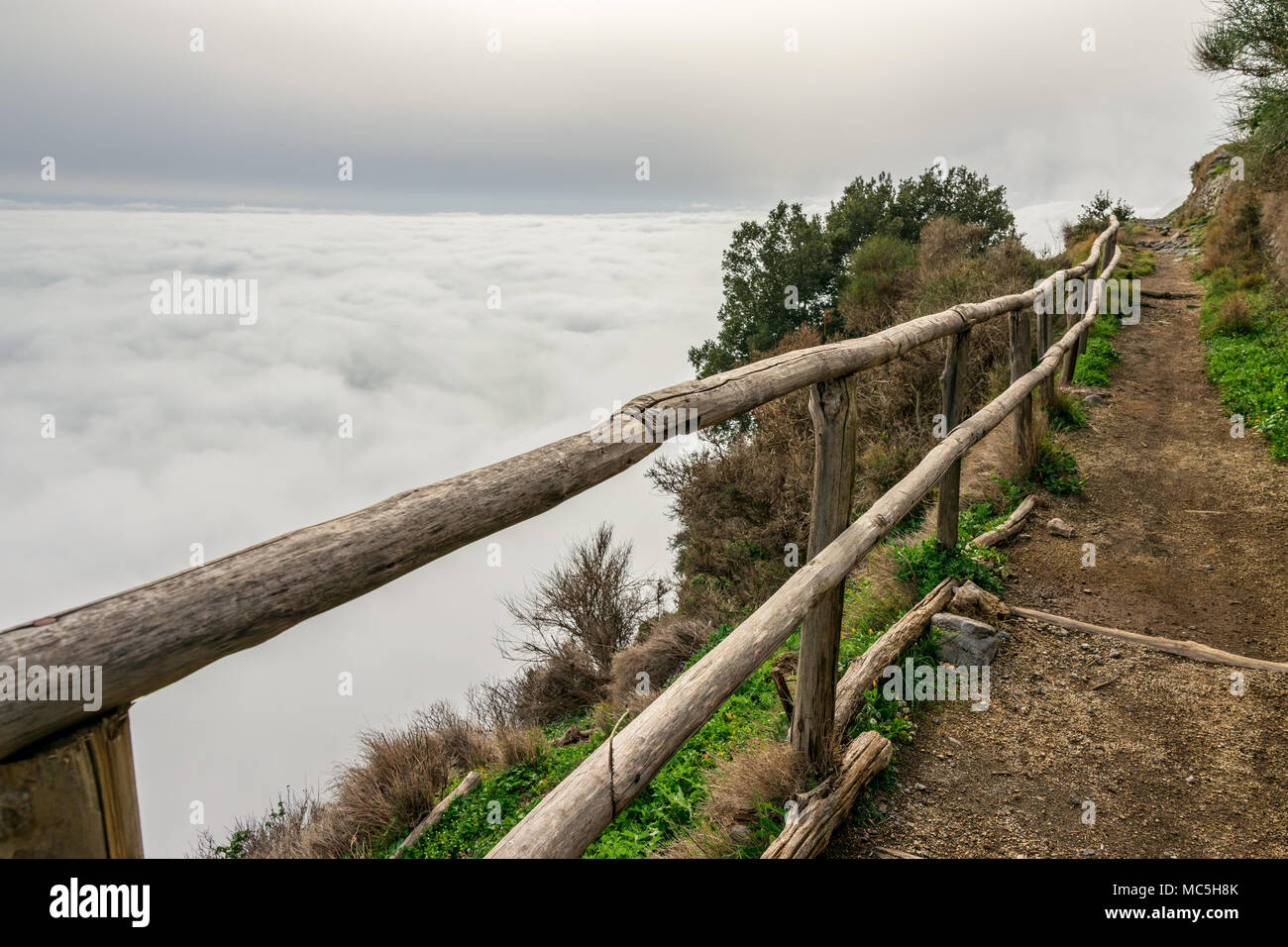 Escursioni in montagna sentiero lungo Bomerano a Positano in Sud Italia con corrimano in legno sul lato del percorso, affacciato sul mare di nuvole e cielo. Foto Stock