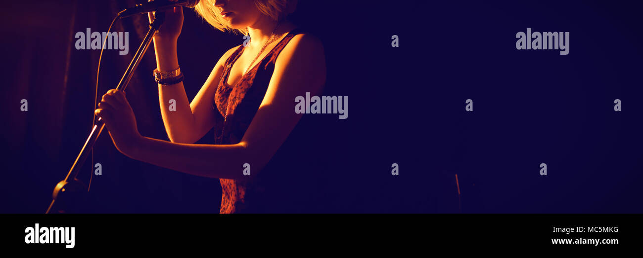 Premurosa donna con microfono al club Foto Stock