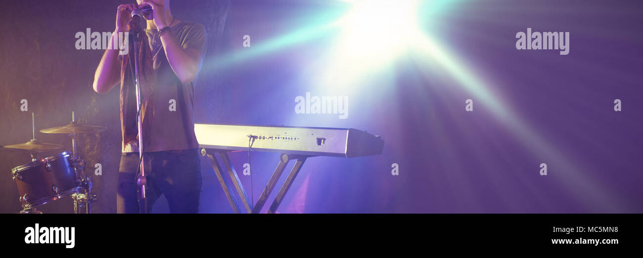 Cantante maschio esibirsi sul palco illuminato in discoteca Foto Stock