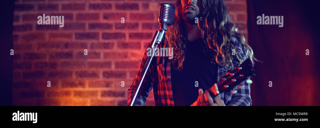 Cantante maschio esecuzione in locale notturno illuminato Foto Stock