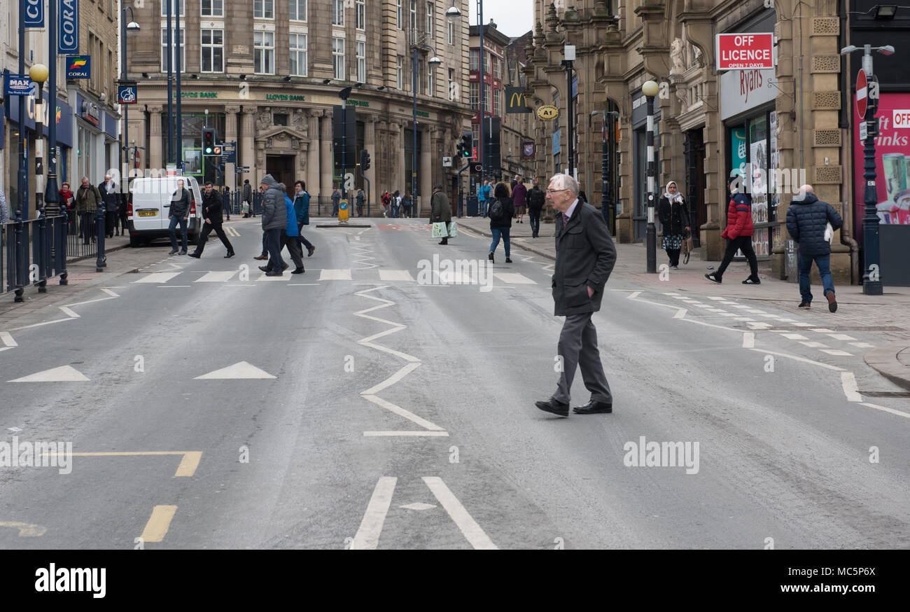 Una vivace scena di strada in un centro cittadino britannico con pedoni che attraversano passeggiate, circondati da architettura storica e negozi Foto Stock