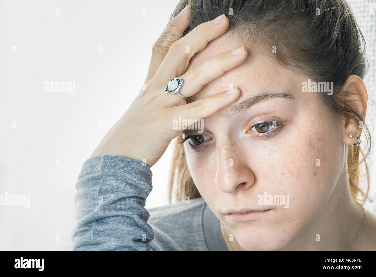 Ragazza adolescente quasi a piangere, triste a casa con la sua mano sulla fronte guardando verso il basso. Foto Stock