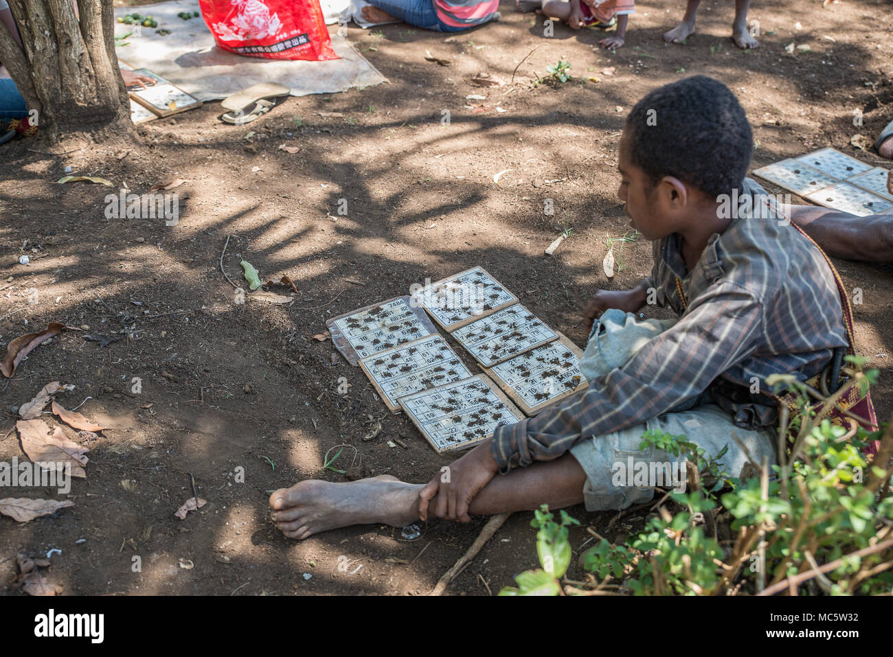 Un ragazzo seduto sul terreno controllando la sua le schede di bingo, area di Goroka, altopiano orientale provincia di Papua Nuova Guinea Foto Stock