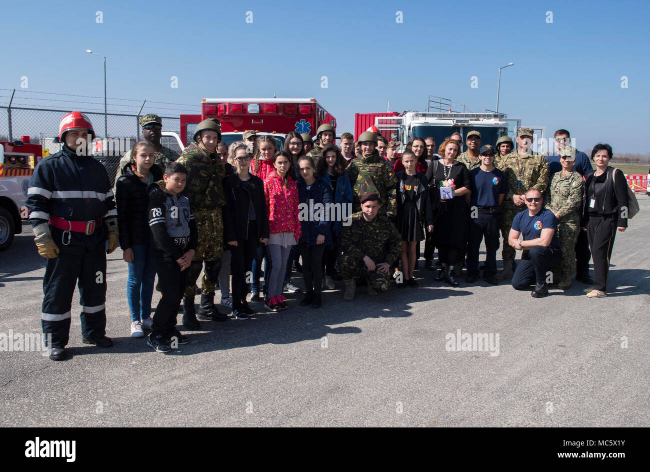 La Romania (30 marzo 2018) marinai dalla base navale di meccanismo di sostegno Deveselu e soldati dal rumeno 99th base militare a prendere una foto di gruppo con i docenti e gli studenti della scuola Deveselu, una locale scuola rumena, durante una comunità relazioni (COMREL) progetto sulla base. NSF Deveselu AAMDS e Romania sono co-localizzato con il rumeno 99th Base Militare e gioca un ruolo chiave nel missile balistico di difesa in Europa orientale. Foto Stock