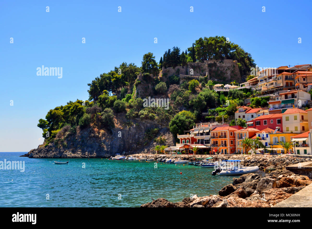 Parga, Epiro - Grecia. Case colorate amphitheatrically costruita accanto al castello di Parga. Giornata soleggiata con cielo blu chiaro Foto Stock