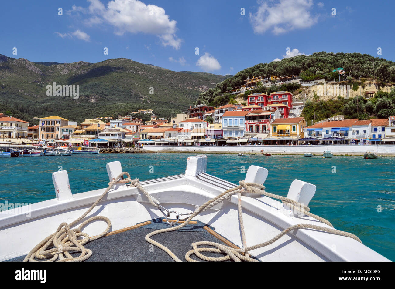 Parga, Epiro - Grecia. Vista panoramica di Parga mentre ci stiamo avvicinando alla città con la barca tradizionale di un uomo nativo che organizza visite guidate del mare Foto Stock