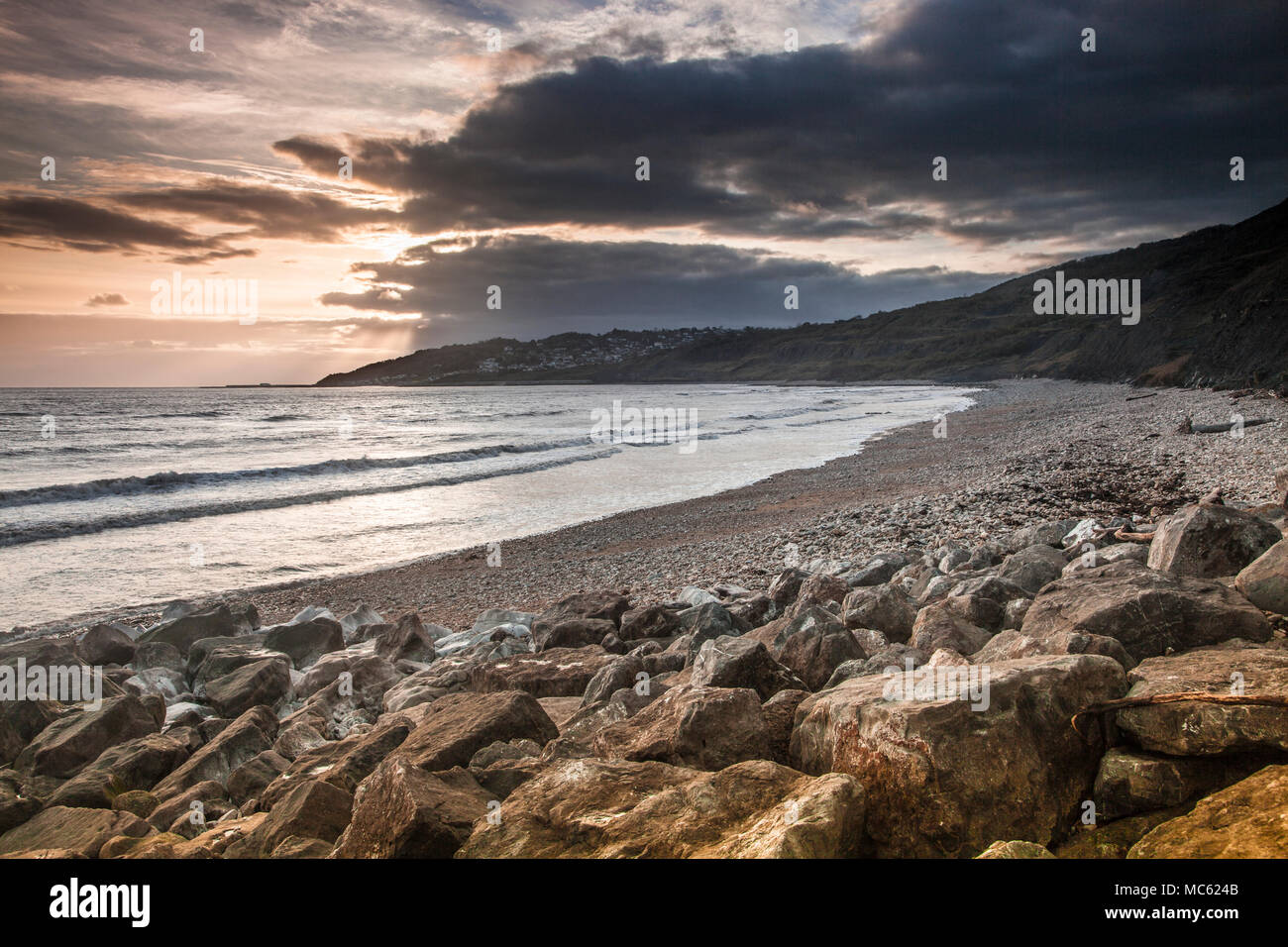 Tramonto sulla spiaggia di Charmouth guardando verso Lyme Regis. Foto Stock