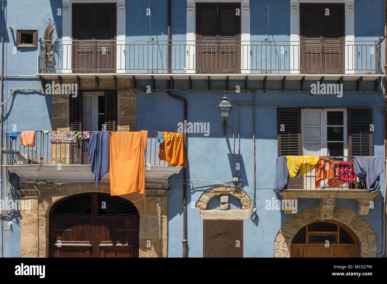 Lavaggio colorati appesi da balconi su un edificio blu con pareti dipinte a Palermo, Sicilia, Italia. Foto Stock