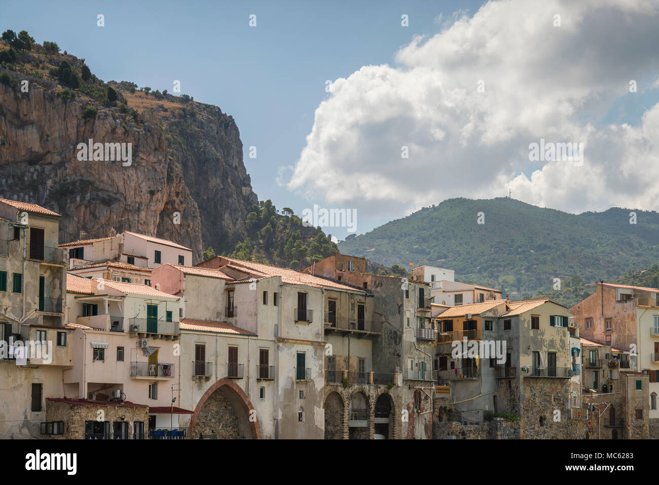 Edifici storici a Cefalu, Sicilia, Italia, con colline rocciose in background. Foto Stock