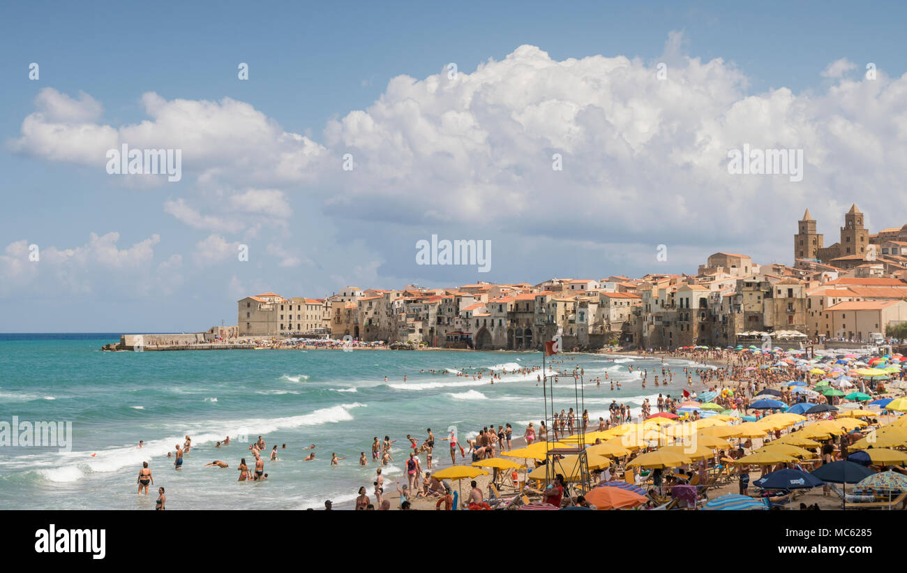 Cefalù, Sicilia, Italia. Ombrelloni riempire la spiaggia di sabbia in una giornata di sole in agosto con una folla di gente che nuotare in mare la sezione giallo è un pagato Foto Stock
