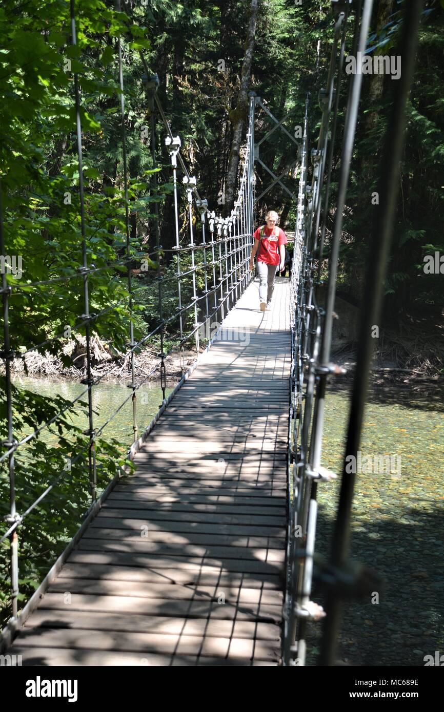 Donna passeggiate attraverso un ponte di sospensione nel Parco Nazionale di Olympic, Stati Uniti di Washington Foto Stock