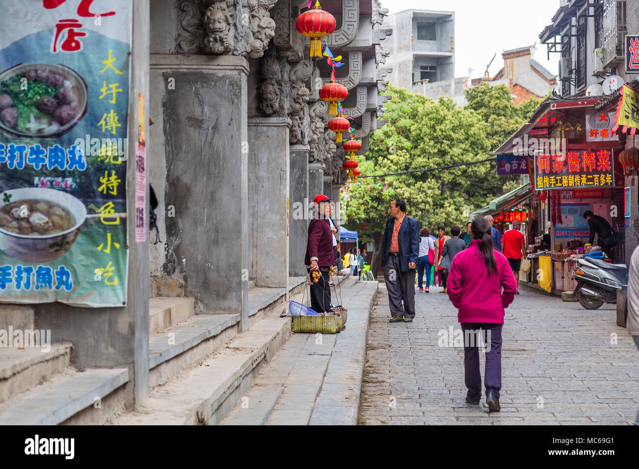 Una donna anziana vende frutta da cestelli su una strada nel borgo antico di Daxu, Guilin, Cina. Foto Stock