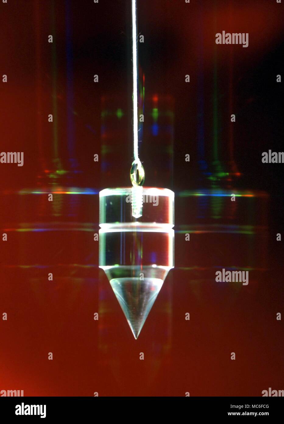 Radioestesia - pendolo pendolo traslucido, fotografati con galaxy effetto arcobaleno auric sfondo Foto Stock