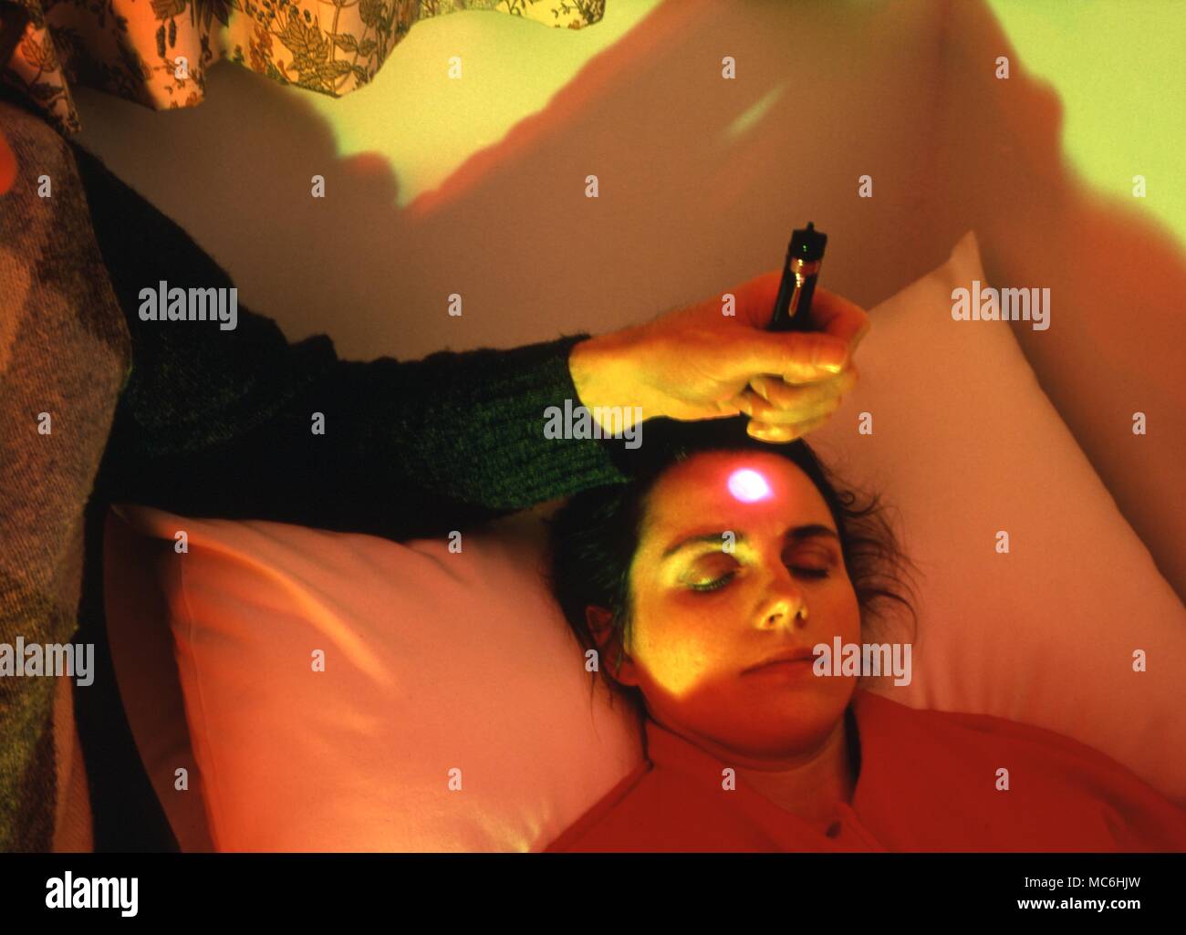Terapia del colore. Proiettare una luce sul frontale di chakra, in una stanza illuminata con colori in omaggio. Foto Stock