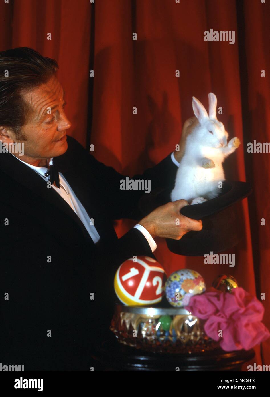 Il mago solleva un coniglio bianco da un cappello che ha appena dimostrato di essere vuoto. Foto Stock