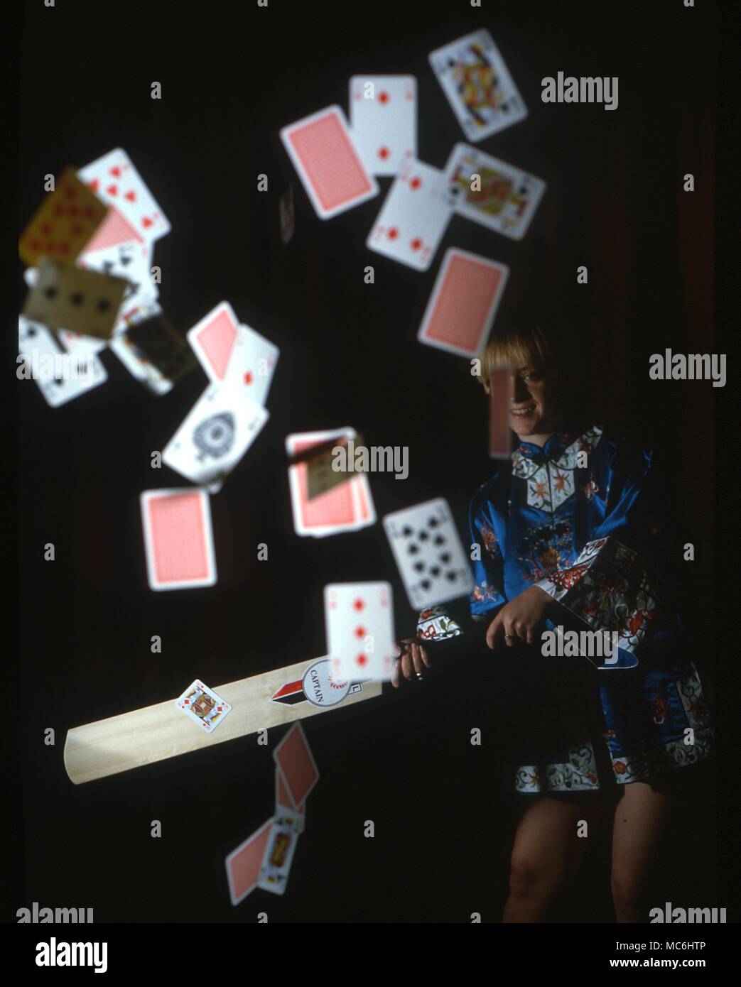 Stage Magic - Battere una carta. Il mago è assistente di scioperi a caduta di un pacco di schede e colpisce uno che aderisce al cricket bat. Questa scheda è identico a quello precedentemente selezionato dal ponte da un membro del pubblico. Foto Stock