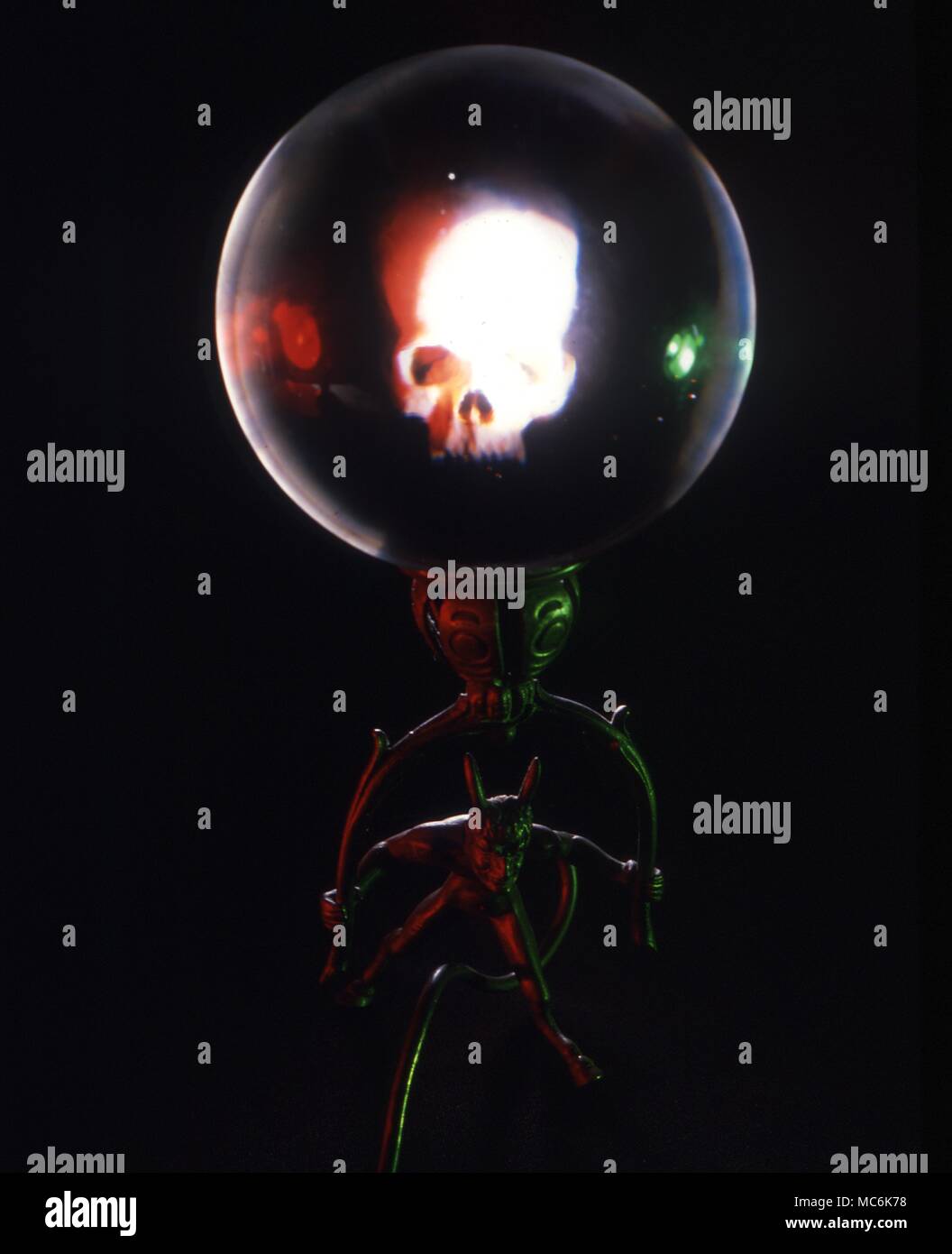 Fissando lo sguardo di cristallo. Cristallo con cranio riflessa nel vetro, sul supporto demoniaca, contro uno sfondo scuro Foto Stock