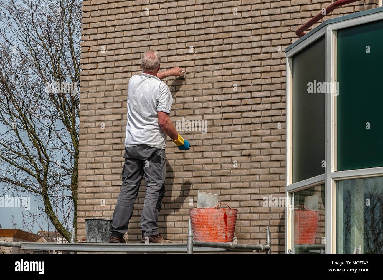 Un muratore è di aggiungere i mattoni di un muro di una casa residenziale Foto Stock