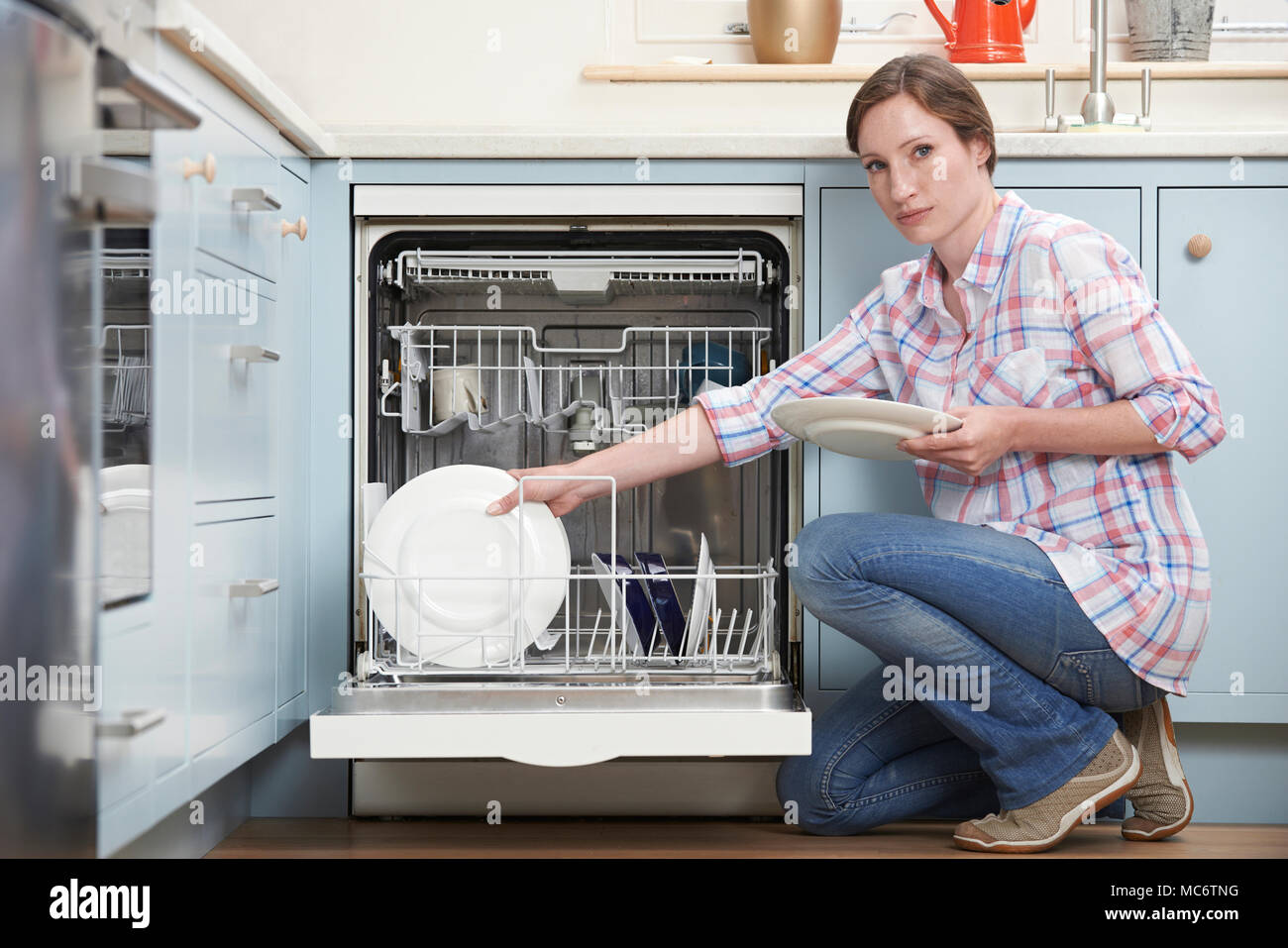 Ritratto di donna Dishwashwasher Caricamento in cucina Foto Stock